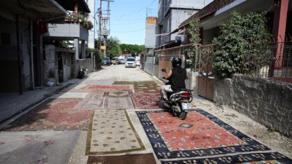 Adana’da mahalle sakinleri asfaltlanmayan yoldaki çukurları halılarla kapattı